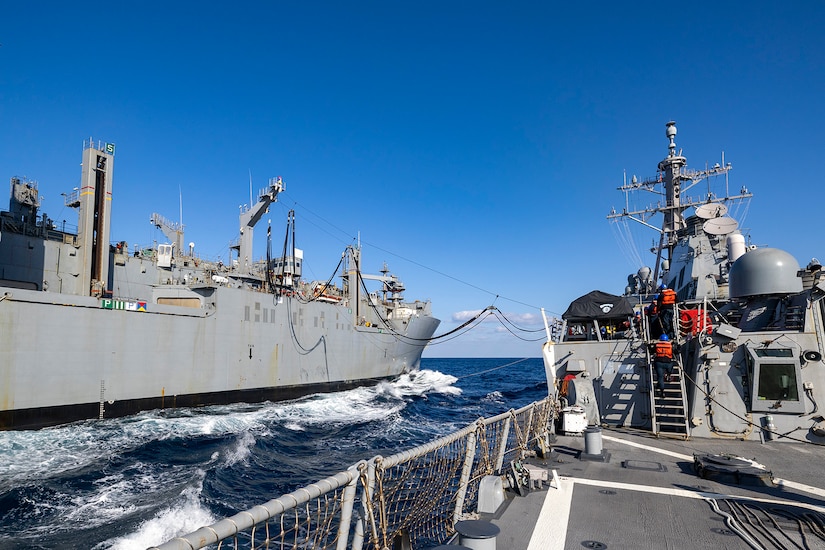 A ship transfers fuel to another ship while in the ocean.