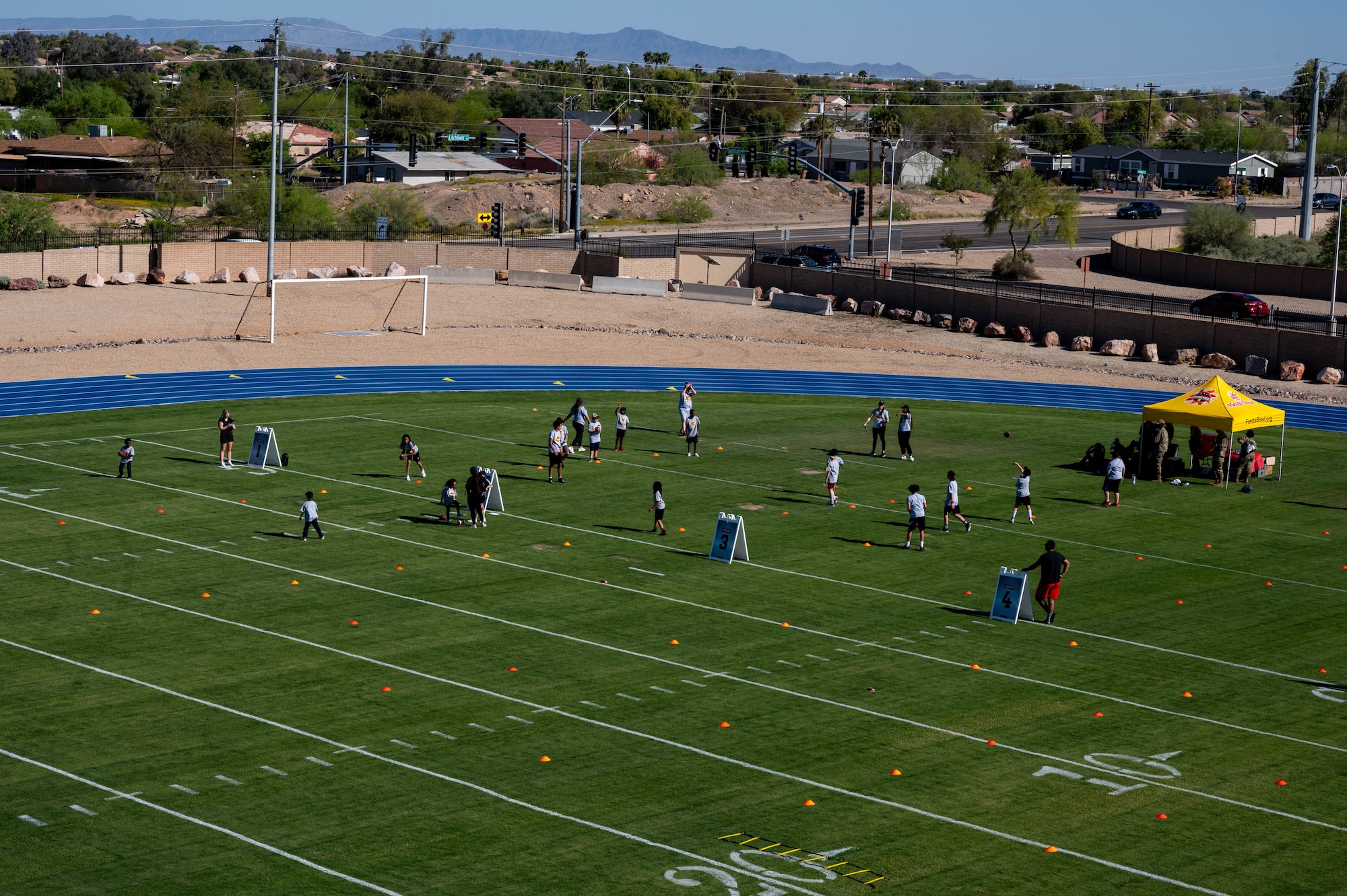Luke Air Force Base children participate in a football training camp during the opening of the Fiesta Bowl field, April 11, 2024, at Luke Air Force Base, Arizona.