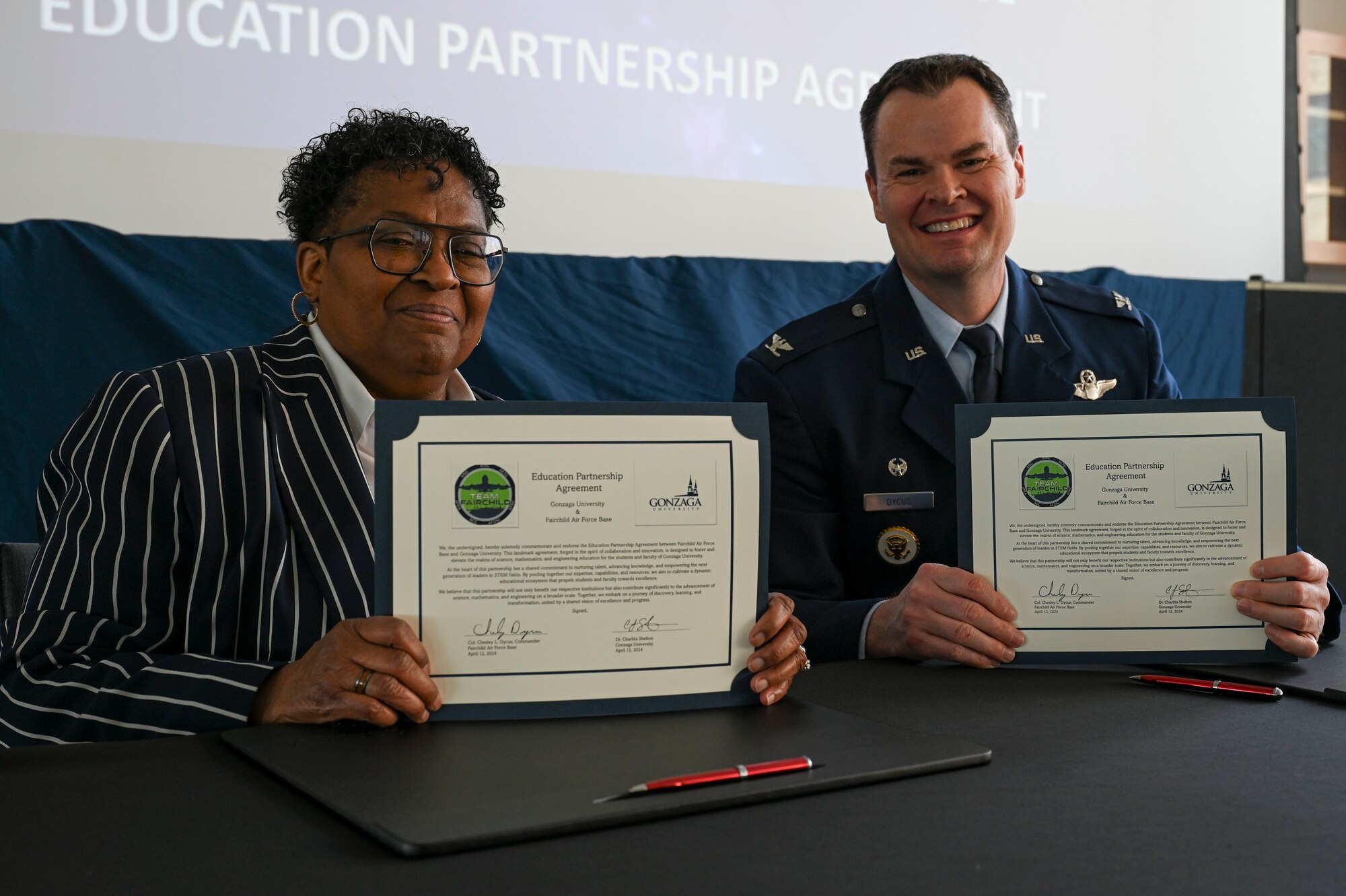 A servicemember and a woman hold signed documents