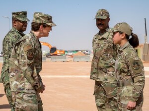Air Force Gen. Jacqueline Van Ovost, commander of U.S. Transportation Command, stands next to one service members while speaking to two others.