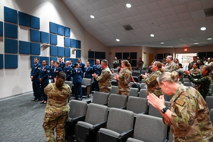 Family members, friends, and fellow Reserve Citizen Airmen applaud a new group of 433rd Airlift Wing and 960th Cyberspace Wing Non-Commissioned Officers during an NCO Induction Ceremony at Joint Base San Antonio-Lackland, Texas on April 6, 2024.