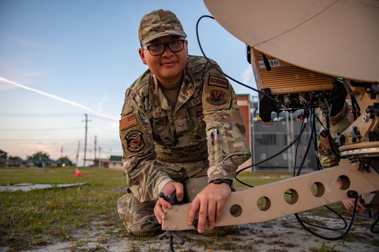A U.S. Airman smiles at the camera holding satellite equipment