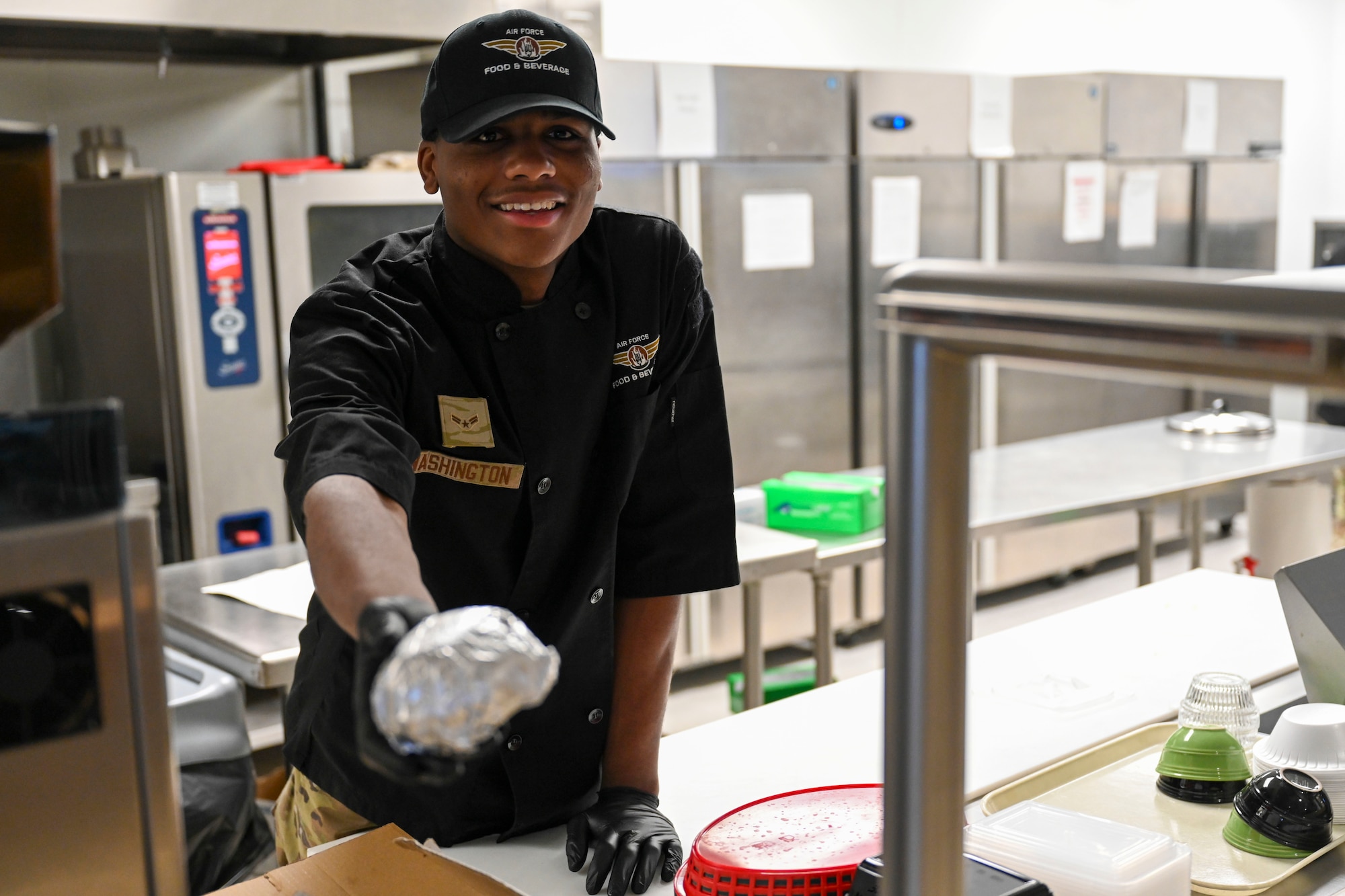 U.S. Air Force Airman 1st Class Jordan Washington, 49th Force Support Squadron food services apprentice, serves a 49er Cafe breakfast sandwich at Holloman Air Force Base, March 21, 2024. The 49er Cafe, located within Club Holloman, launched a new breakfast and lunch menu with a selection of salads, sandwiches, wraps, and grab-and-go items that provide everyone with easy and healthful options. (U.S. Air Force photo by Airman 1st Class Michelle Ferrari)