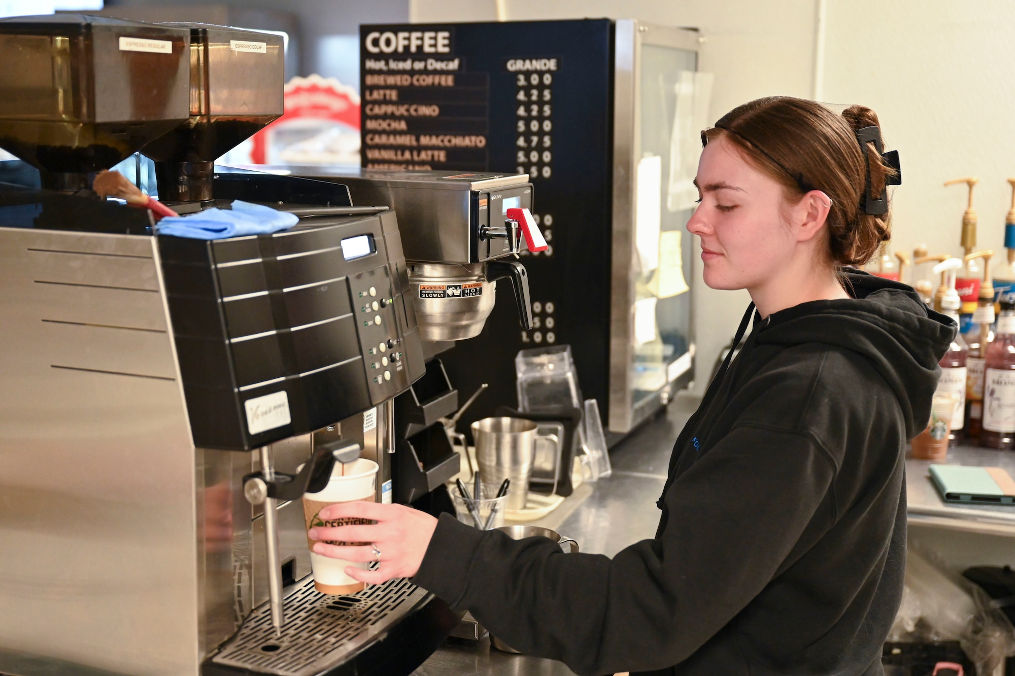 Jennifer Layman, 49th Force Support Squadron barista, prepares a coffee drink with espresso in the 49er Cafe at Holloman Air Force Base, New Mexico, March 21, 2024. The 49er Cafe unveiled a new menu recently featuring brewed awakenings and a selection of coffee drinks. (U.S. Air Force photo by Airman 1st Class Michelle Ferrari)