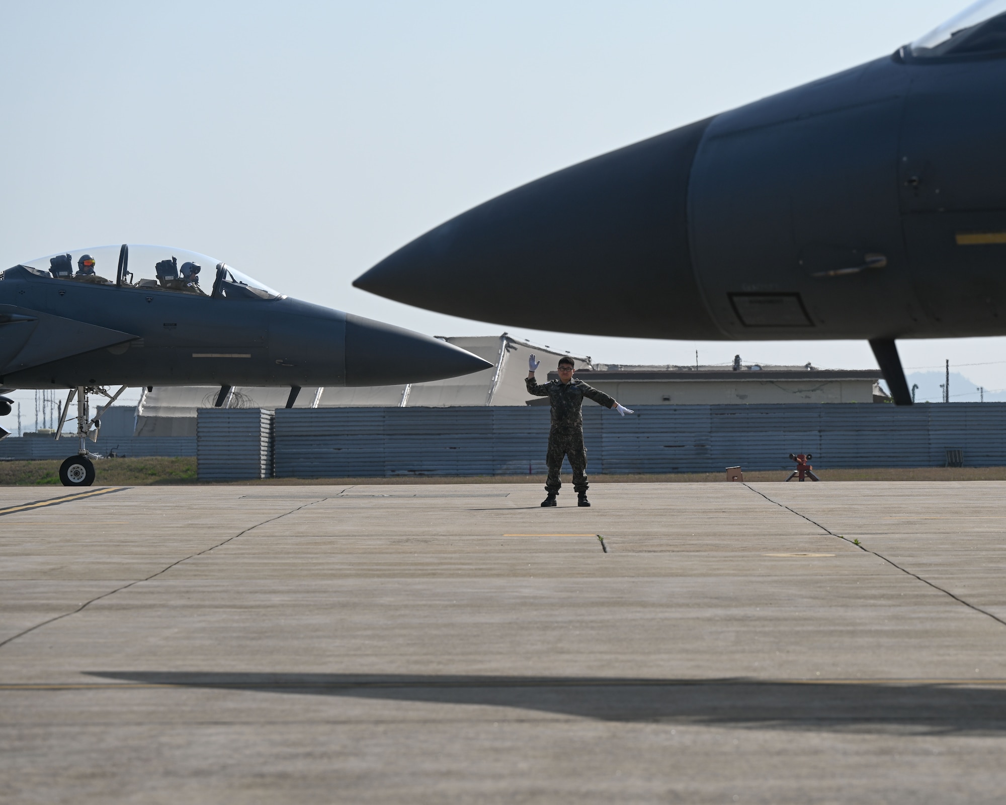 A member of the Republic of Korea Air Force directs a ROKAF F-15K Slam Eagle on the taxiway.