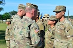 Pfc. Cassandra Vazquez receives an Army Achievement Medal from the Georgia Army National Guard command team of Maj. Gen. Dwayne Wilson and Command Sgt. Maj. John Ballenger during a battle handoff ceremony April 13, 2024, in Fort Stewart, Ga.