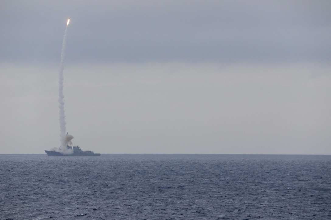 A missile is fired into the sky from a military ship.