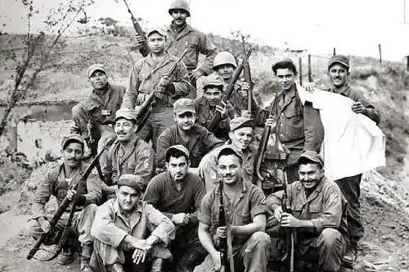 A group of soldiers pose for a black and white photo while holding weapons.