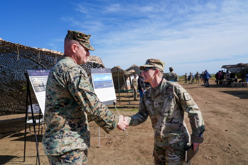 Two uniformed service members shake hands.