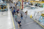 A photo of the inside of a factory with people walking down a designated path.