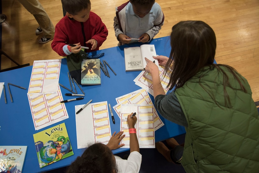 Overhead photo of an adult helping children write their names on labels.