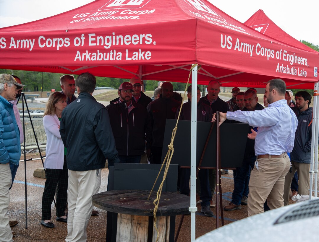 Group of people standing under a tent getting a project briefing.