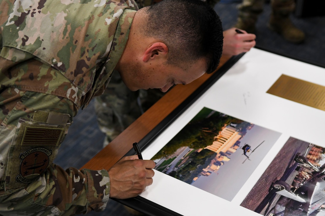 U.S. Air Force Master Sgt. Matthew Trissel, 1st Helicopter Squadron mission control operations superintendent, signs the heritage display for the squadron’s 80th anniversary event at Joint Base Andrews, Md., April 11, 2024.