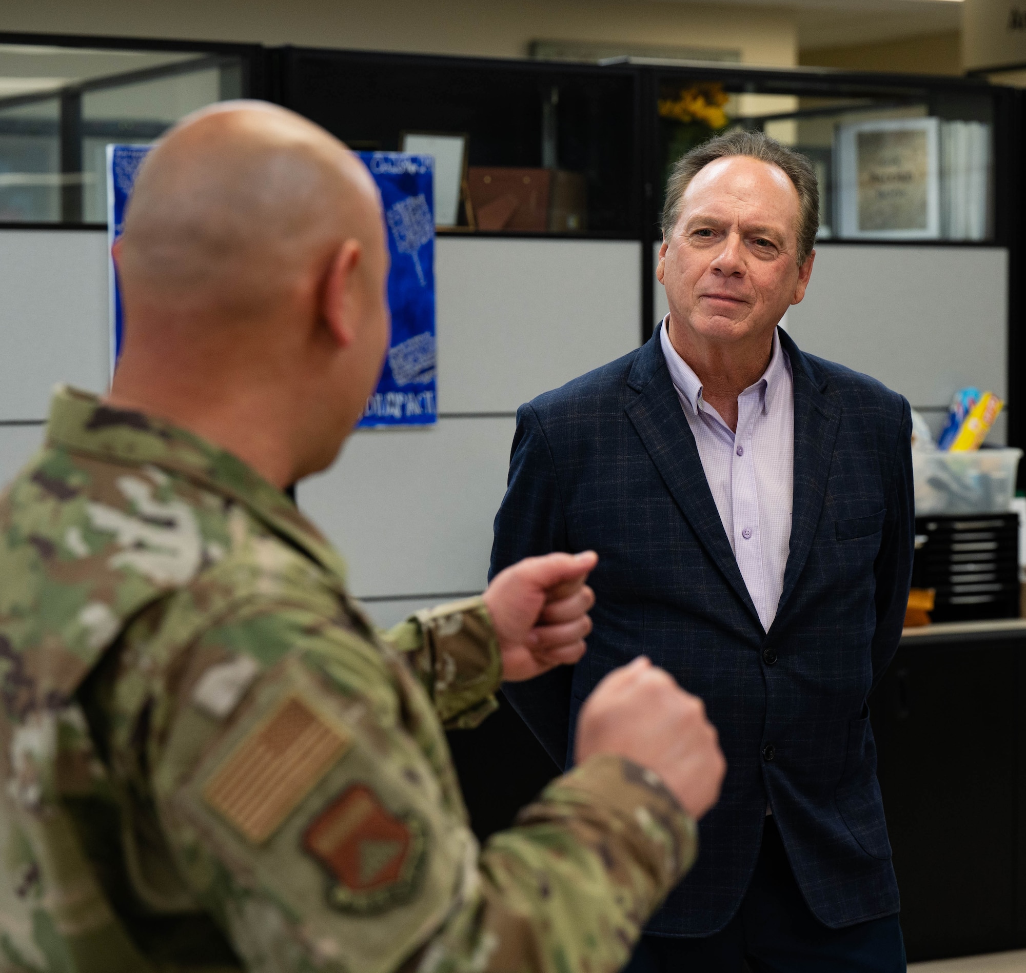 Two men stand in a room and have a conversation.