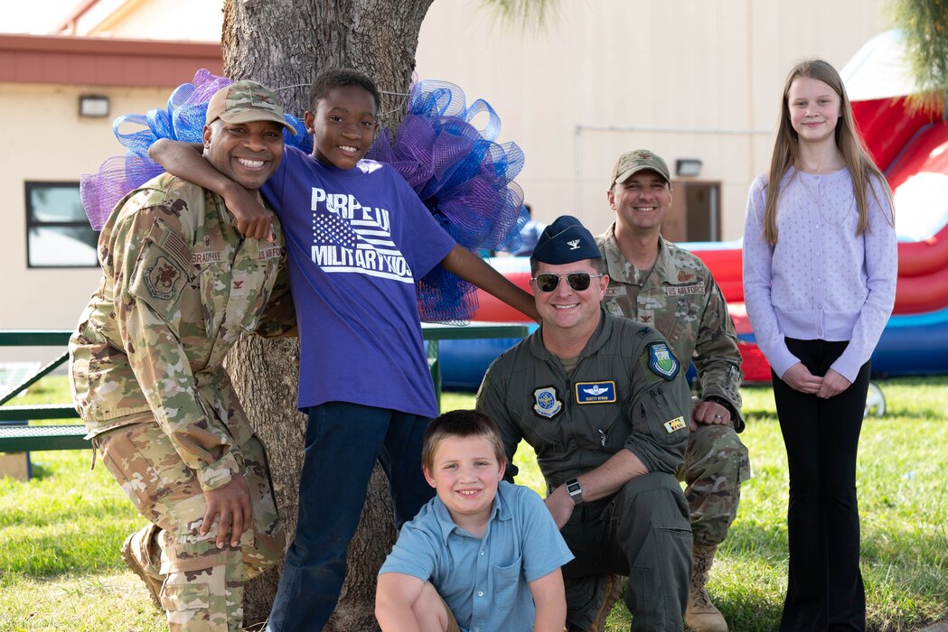 Airmen take a photo with military children