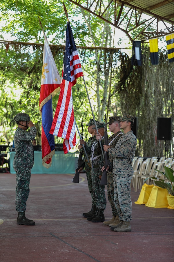 Philippine Marine Corps Capt. Randy Agcaoici, left, the company commander for the 5th Marine Company, Marine Battalion Landing Team 5, 1st Marine Brigade, salutes the Philippine and the U.S. flags during the opening ceremony of Marine Exercise 2024 near Cotabato City, Mindanao, Philippines, April 8, 2024. MAREX 2024 is a bilateral exercise between the U.S. Marine Corps and the Philippine Marine Corps designed to further enhance relationships, interoperability, and combined arms capabilities in a realistic training environment. (U.S. Marine Corps photo by Lance Cpl. Andrew Whistler)