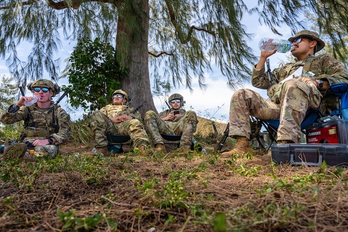 U.S. Air Force landing zone safety officers assigned to the 3rd Expeditionary Operations Support Squadron out of Joint Base Elmendorf-Richardson, Alaska, take five to hydrate during Exercise Agile Reaper 24-1 at Tinian Forward Operating Site, Northern Mariana Islands, April 10, 2024. Tinian FOS is an austere environment next to Tinian International Airport, and while it began as a barren patch of grass, in less than 24 hours, a few dozen Airmen stood up and began operating it as a fully mission-capable forward operating site comprised of approximately 100 Airmen with all the necessary military support functions to service and launch military aircraft, namely JBER’s F-22 Raptors from the 90th Fighter Squadron. (U.S. Air Force photo by Tech. Sgt. Curt Beach)