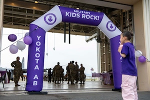 A child stands in front of an archway that says "Military Kids Rock".
