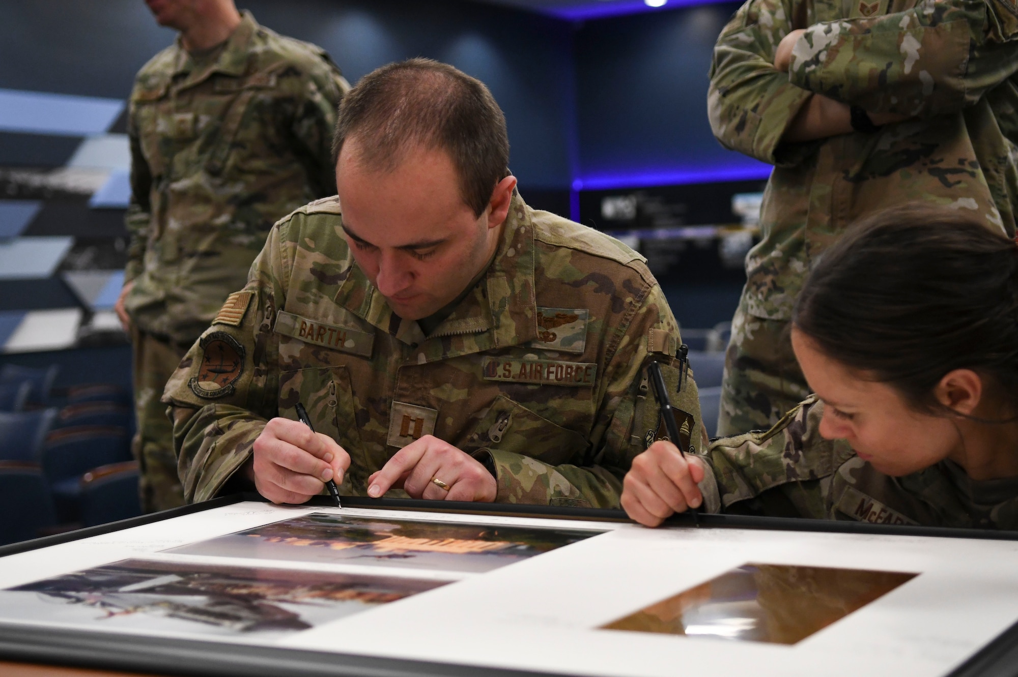 U.S. Air Force Capts. Andrew Barth, left, and Dena McFadden, right, members of the 1st Helicopter Squadron, inscribe messages on the squadron’s 80th Anniversary heritage display at Joint Base Andrews, Md., April 11, 2024.