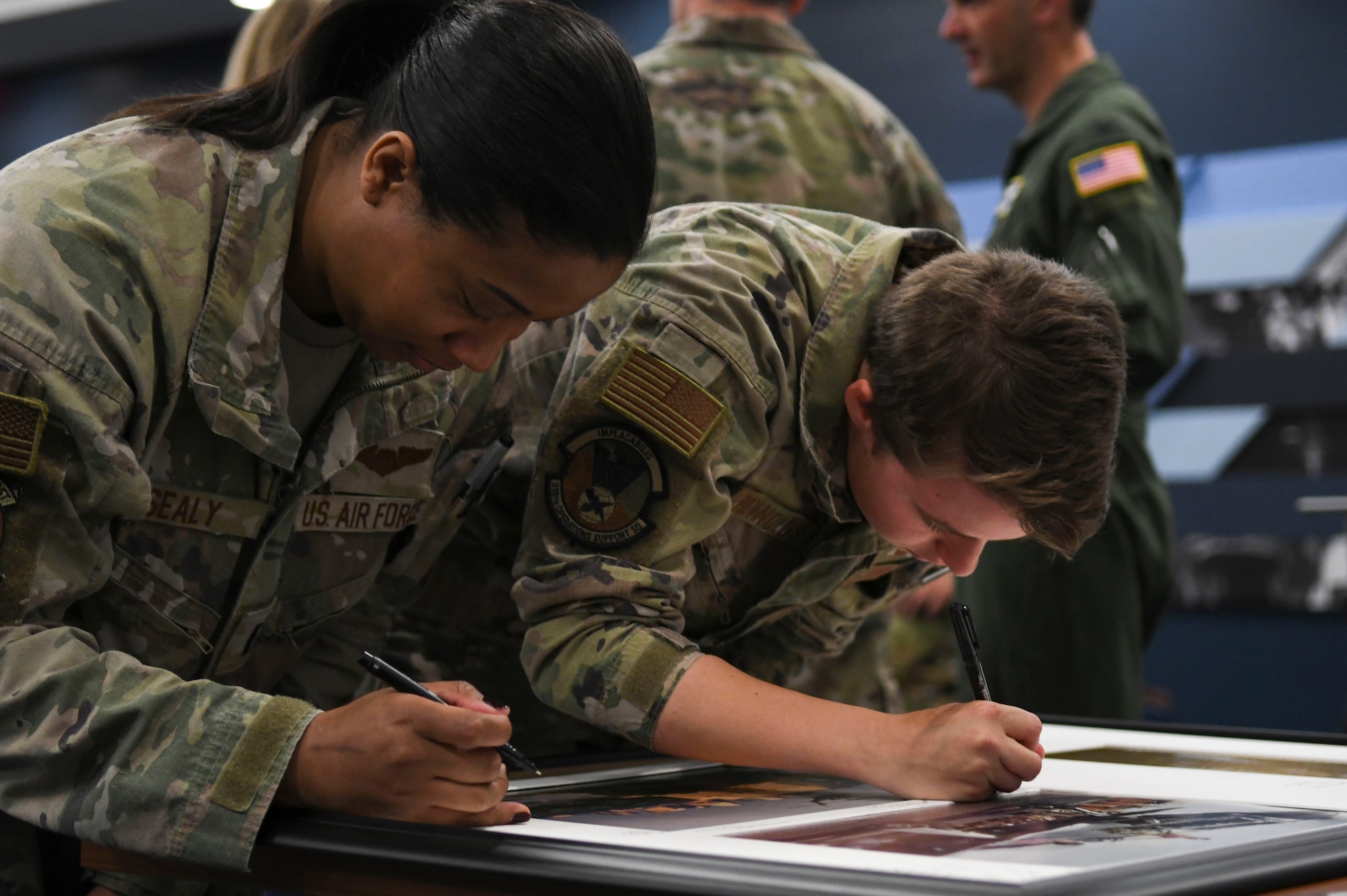 U.S. Air Force 1st Lts. Christyna Sealy, left, and Krisanna Reynolds, right, both members of the 1st Helicopter Squadron, leave behind notes on the squadron’s 80th anniversary heritage display at Joint Base Andrews, Md., April 11, 2024.