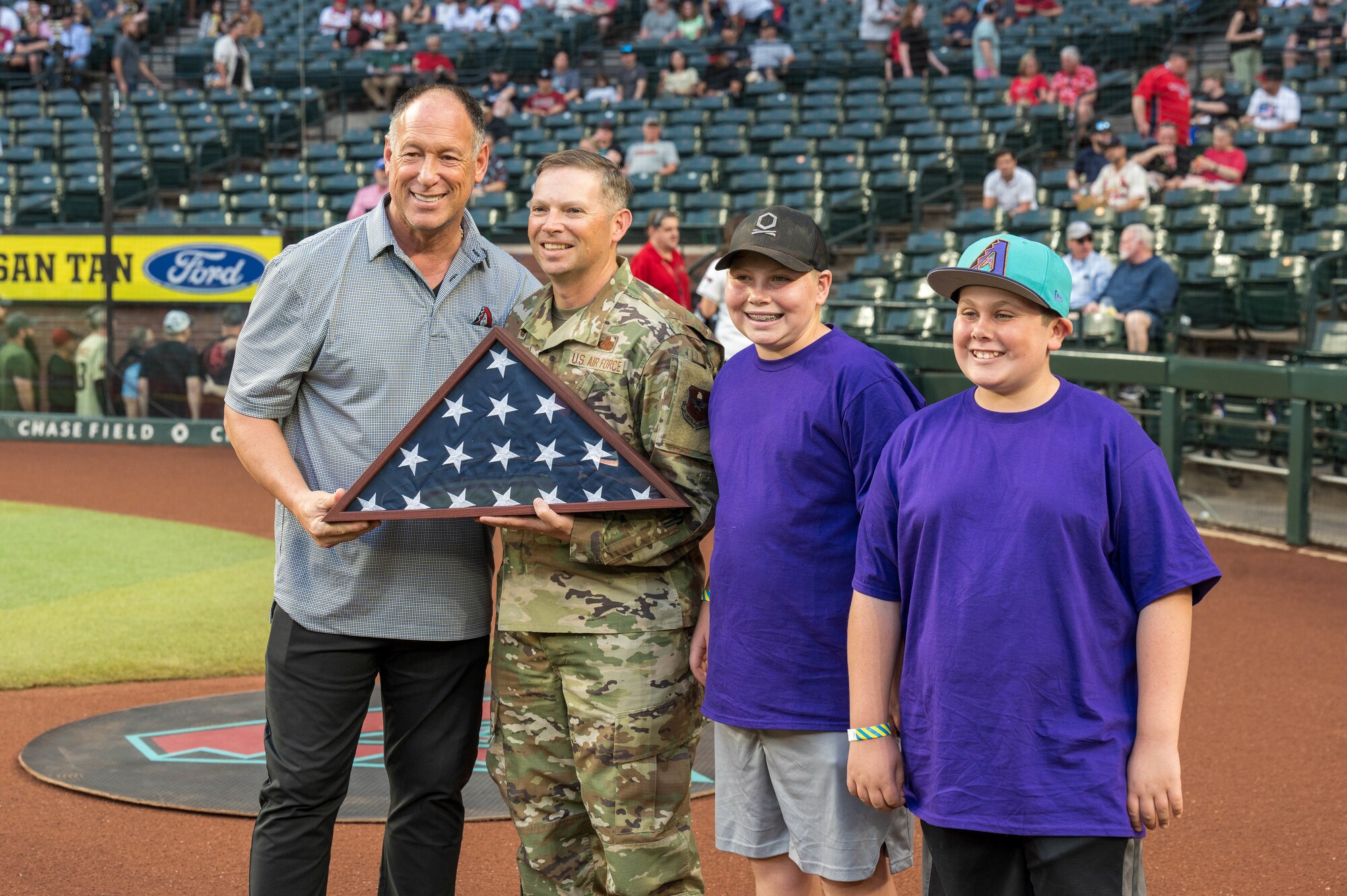 U.S. Air Force Col. Peter Abercrombie, 56th Mission Support Group commander, presents a U.S. flag to Luis Gonzalez, Arizona Diamondbacks special assistant to the president, during a Diamondbacks game, April 12, 2024, in Phoenix, Arizona.