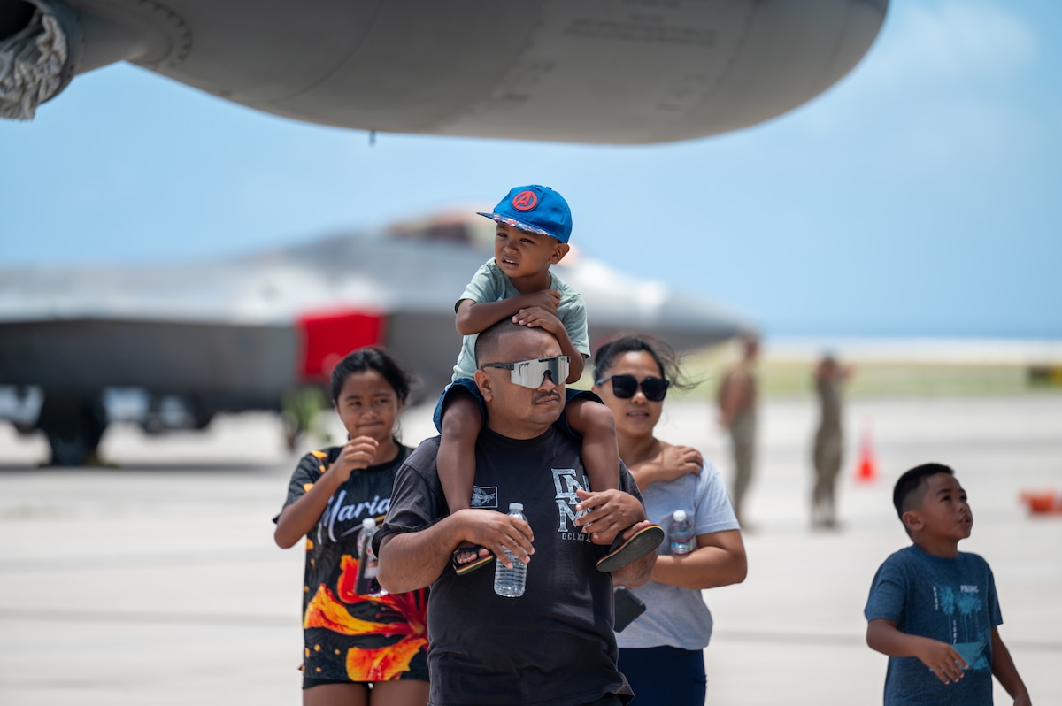 A family walks around a community day event hosted by the 15th Wing and 3rd Air Expeditionary Wing at Saipan, Northern Marianas Islands, April 13, 2024. During the event participants explored three military aircraft and had the opportunity to talk to Airmen about their jobs and the capabilities of the aircraft. (U.S. Air Force photo by Senior Airman Mark Sulaica)