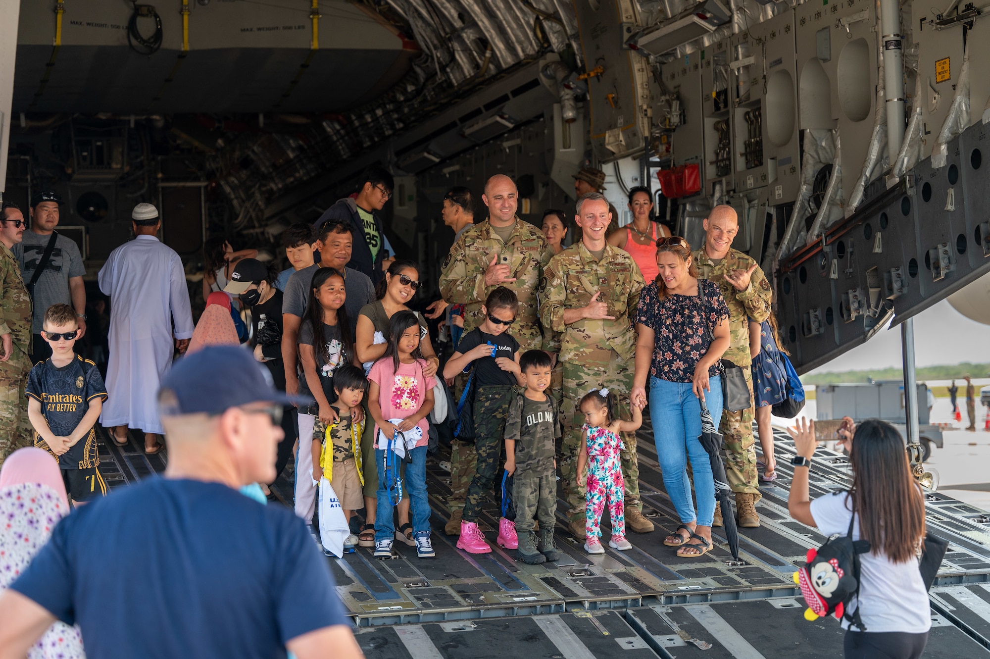 People take a group photo with Airmen during a community day event at Saipan, Northern Marianas Islands, April 13, 2024. During the event participants explored three military aircraft and had the opportunity to talk to Airmen about their jobs and the capabilities of the aircraft. (U.S. Air Force photo by Senior Airman Mark Sulaica)