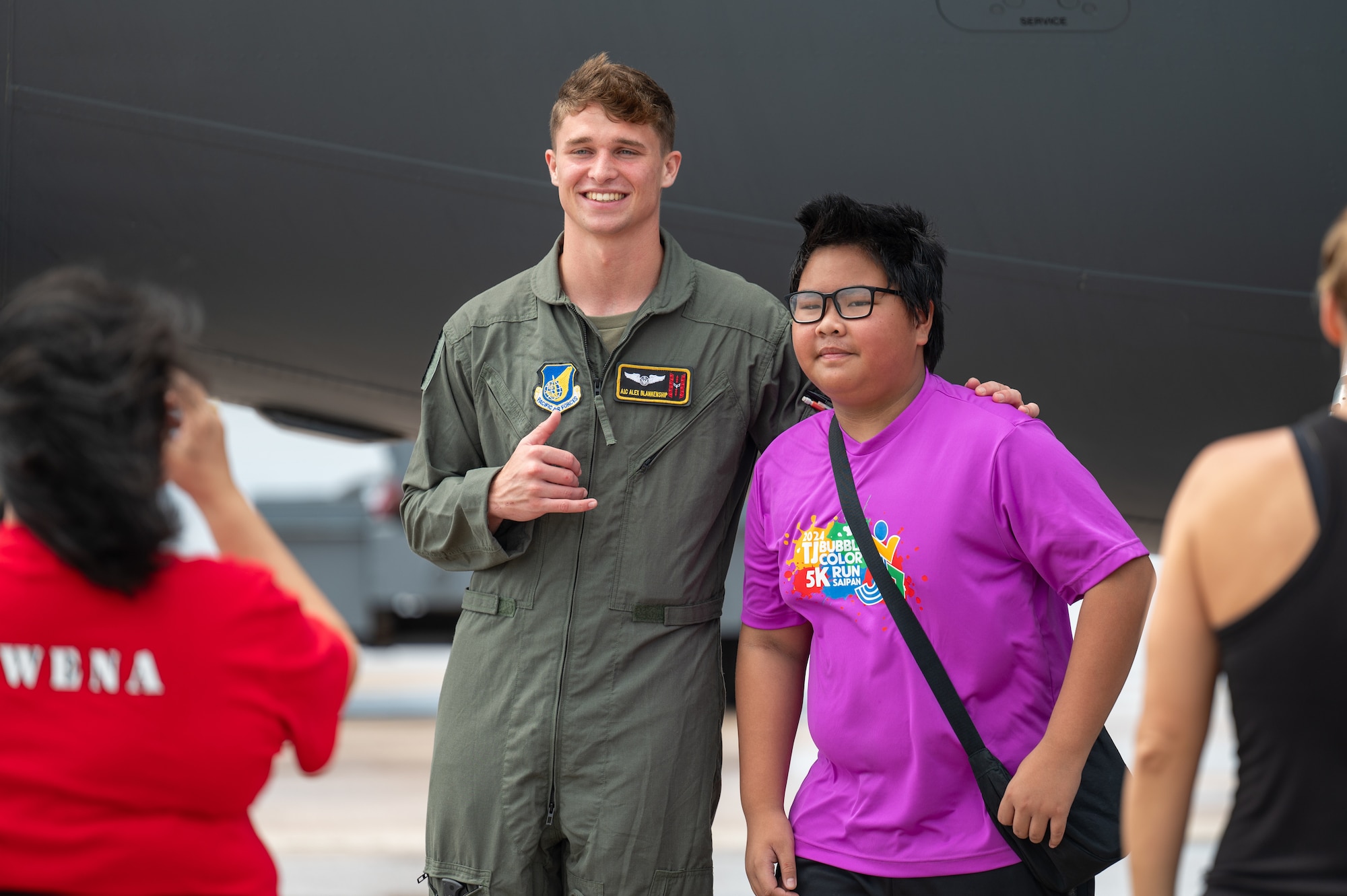 Airman 1st Class Alex Blankenship, 535th Airlift Squadron loadmaster,  takes a photo with a kid during a community day at Saipan, Northern Marianas Islands, April 13, 2024. Airmen during the event had the opportunity to speak and inspire participants to recruit the next generation of Airmen. (U.S. Air Force photo by Senior Airman Mark Sulaica)