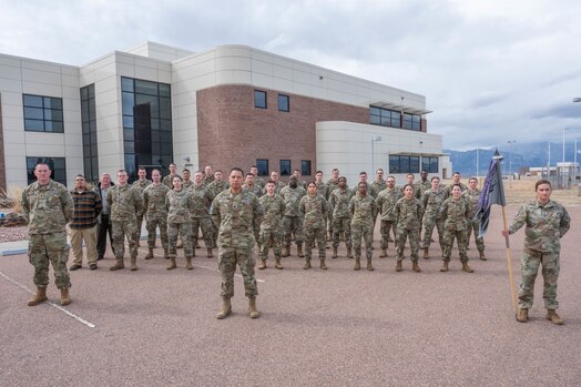  U.S. Space Force Senior Master Sgt. Kathleen Nieuwenhuis, senior enlisted leader for the 5th Electromagnetic Warfare Squadron, far right, holds the ceremonial guidon during the 5th EWS squadron photo at Peterson Space Force Base, Colorado, March 14, 2024. Nieuwenhuis serves as the 5th EWS Guardian and Airmen Development Program coordinator, an initiative which aims to deliver professional development opportunities for its servicemembers. (U.S. Space Force photo by Emily Peacock)