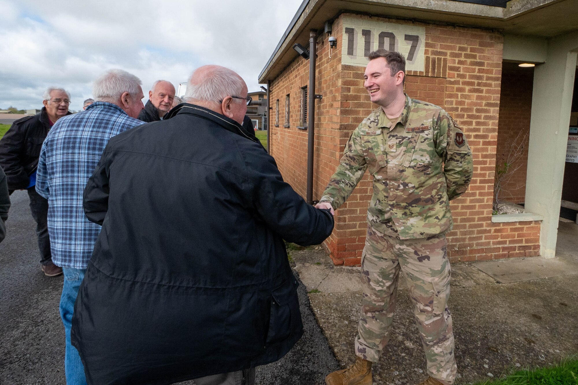 Greenham Common control tower volunteers shake hands with an Airman.