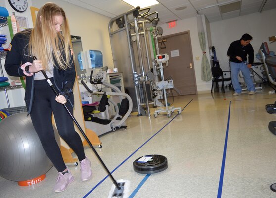 Making it a clean sweep of recovery…A Roomba relay was employed as part of training in recovery from hypothetical scenario involving injuries to sight, sinew and senses. The relay and other activities were presented to Naval Hospital Bremerton’s Physical Therapy department team in conjunction with April designated as Occupational Therapy Month. Ms. Teri Nyblom, NHB certified occupational therapist assistant, presented her Physical Therapy counterparts with practical, hands-on instruction of what occupational therapists offer any eligible beneficiaries during their recovering, recuperating and rehabilitating process. Here, Hannah Leon, physical therapist, works a rotator cuff tear as part of the relay designed to provide gentle strengthening for her shoulder (Official Navy photo by Douglas H Stutz, NHB/NMRTC Bremerton public affairs officer).