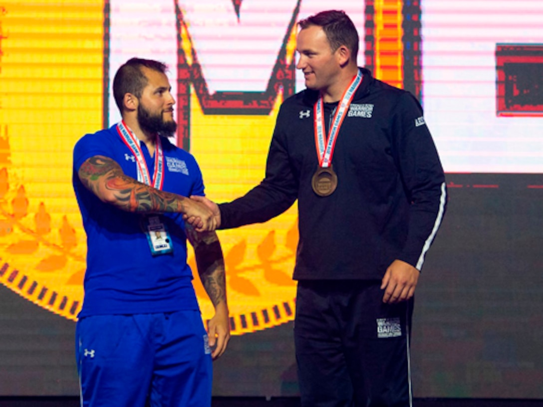 U.S. Army SSG Ross Alewine, right, is congratulated by Silver Medalist U.S. Air Force SrA Rafael Morfinenciso, center, and Bronze Medalist U.S. Army SSG Altermese Kendrick after Alewine won the Gold Medal as Ultimate Champion during the Closing Ceremony at the 2018 Department of Defense Warrior Games.