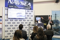 Attendees gather at the NAVSEA booth at the Sea-Air-Space 2024 exposition to listen to NSWC IHD Deputy Technical Director Steve Anthony's presentation on the command’s role in rebuilding the Nation’s industrial base in National Harbor, Maryland, April 10.