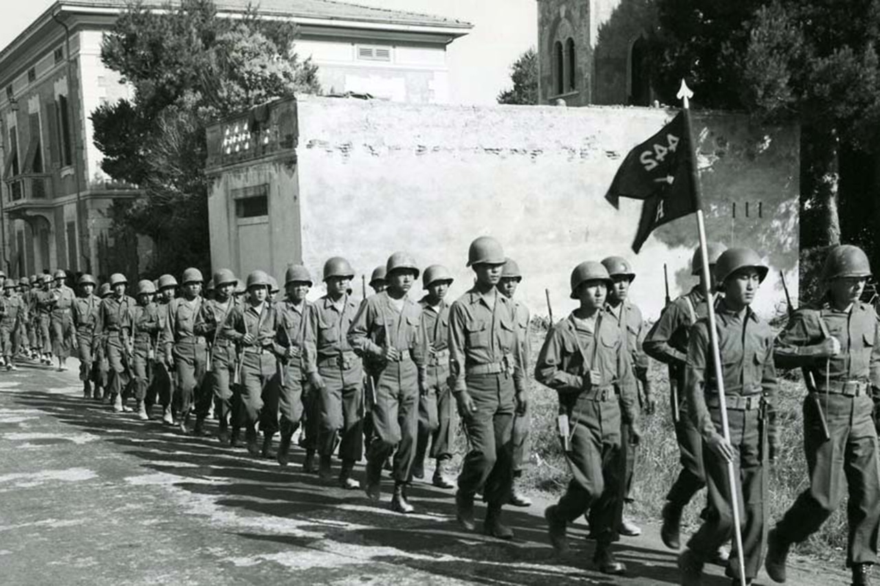 Two long lines of uniformed service members march in formation.