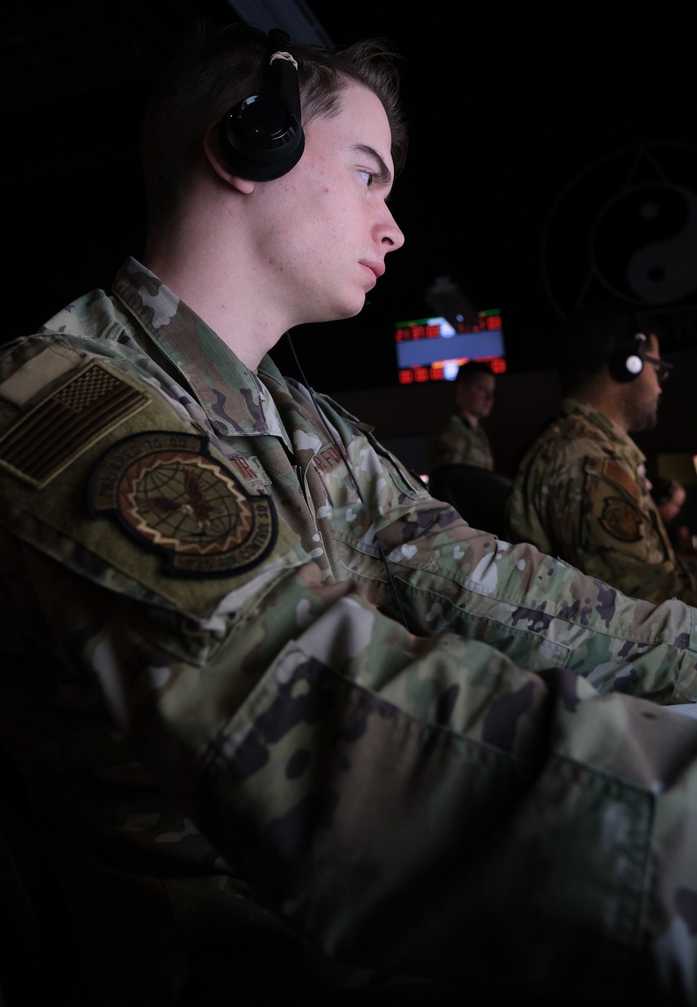 photo of US military personnel wearing headphones working at computers
