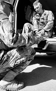 A medic treats blisters on the feet of Sgt. Brandon Elliot after the 12-mile road march during the Illinois Army National Guard’s Best Warrior Competition, April 12-14, at Sparta Training Area in Sparta, Illinois.