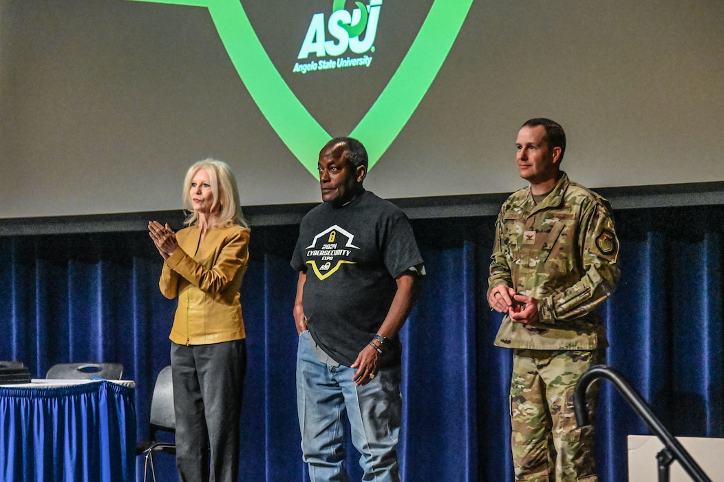U.S. Air Force Col. Christopher Corbett (right), 17th Training Wing Deputy Commander, Angelo State University President Ronnie Hawkins (middle), and San Angelo Mayor Brenda Gunter (left), stand on the stage at the 2024 Youth Cybersecurity Workshop and Expo at Angelo State University, San Angelo, Texas April 5, 2024. The expo was held to emphasize the importance of the cybersecurity career field in both the civilian and military spaces. (U.S. Air Force photo by Airman James Salellas)