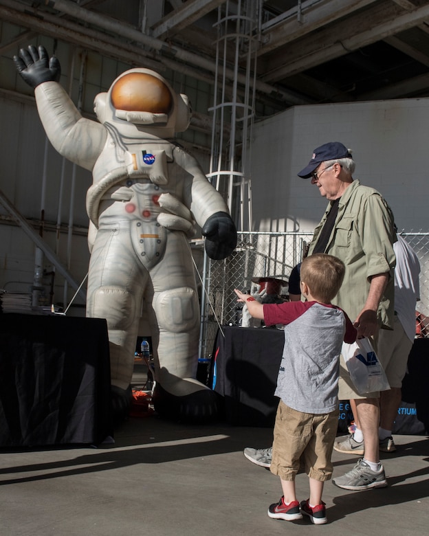 A photo of two people looking at an inflatable astronaut.