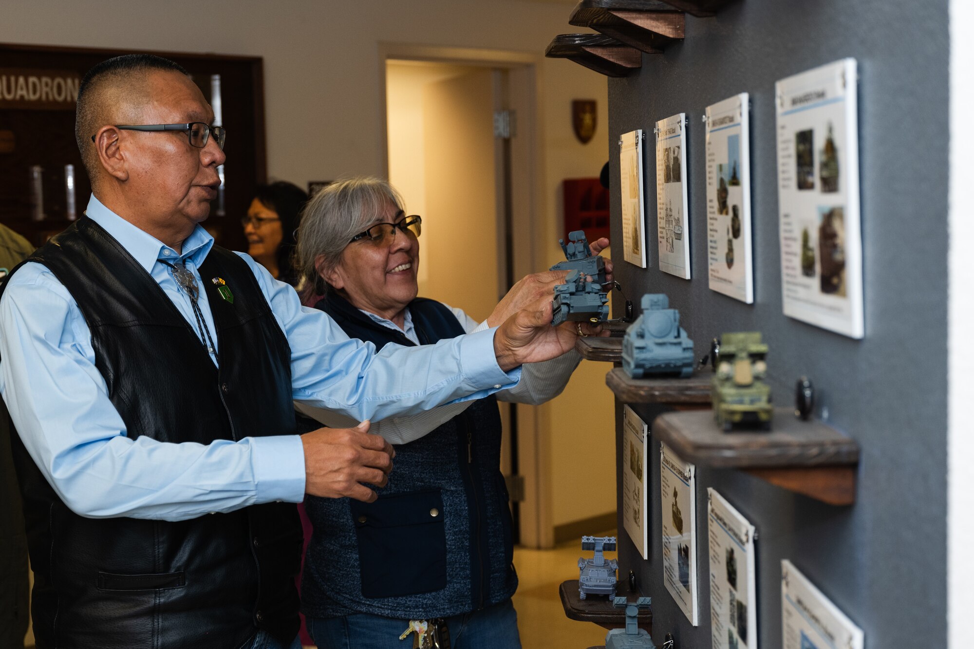 Kelton Starr, Mescalero Tribe education director, left, and Thora Walsh-Padilla, Mescalero Tribe president, examine a display in the 29th Attack Squadron showcasing figurines of service to air threats for the MQ-9 Reaper at Holloman Air Force Base, New Mexico, April 1, 2024.