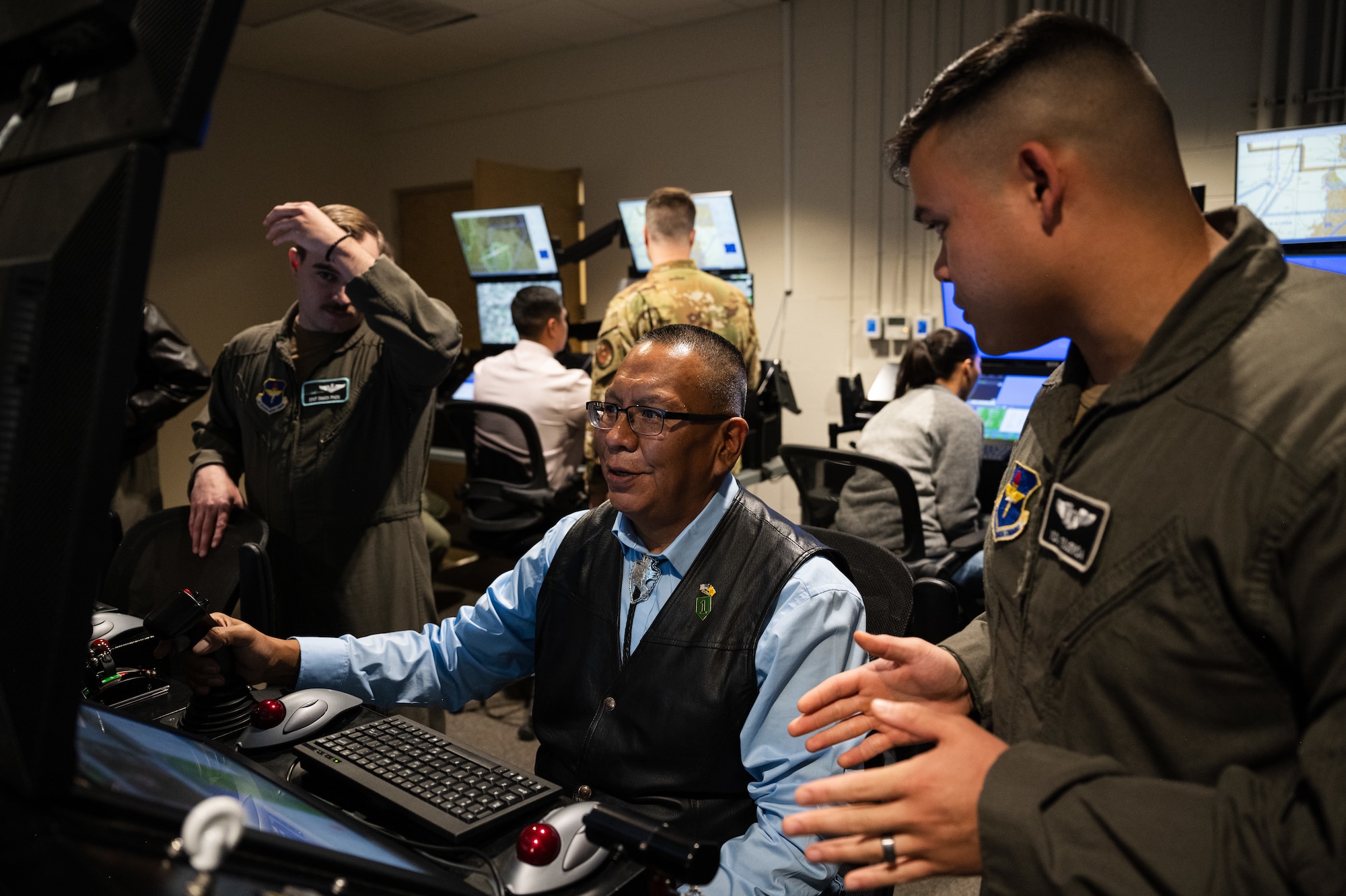 U.S. Air Force Capt. Drake Figueroa, 29th Attack Squadron MQ-9 Reaper pilot, right, explains how MQ-9 training simulators operate to Kelton Starr, Mescalero Tribe education director, left, at Holloman Air Force Base, New Mexico, April 1, 2024.
