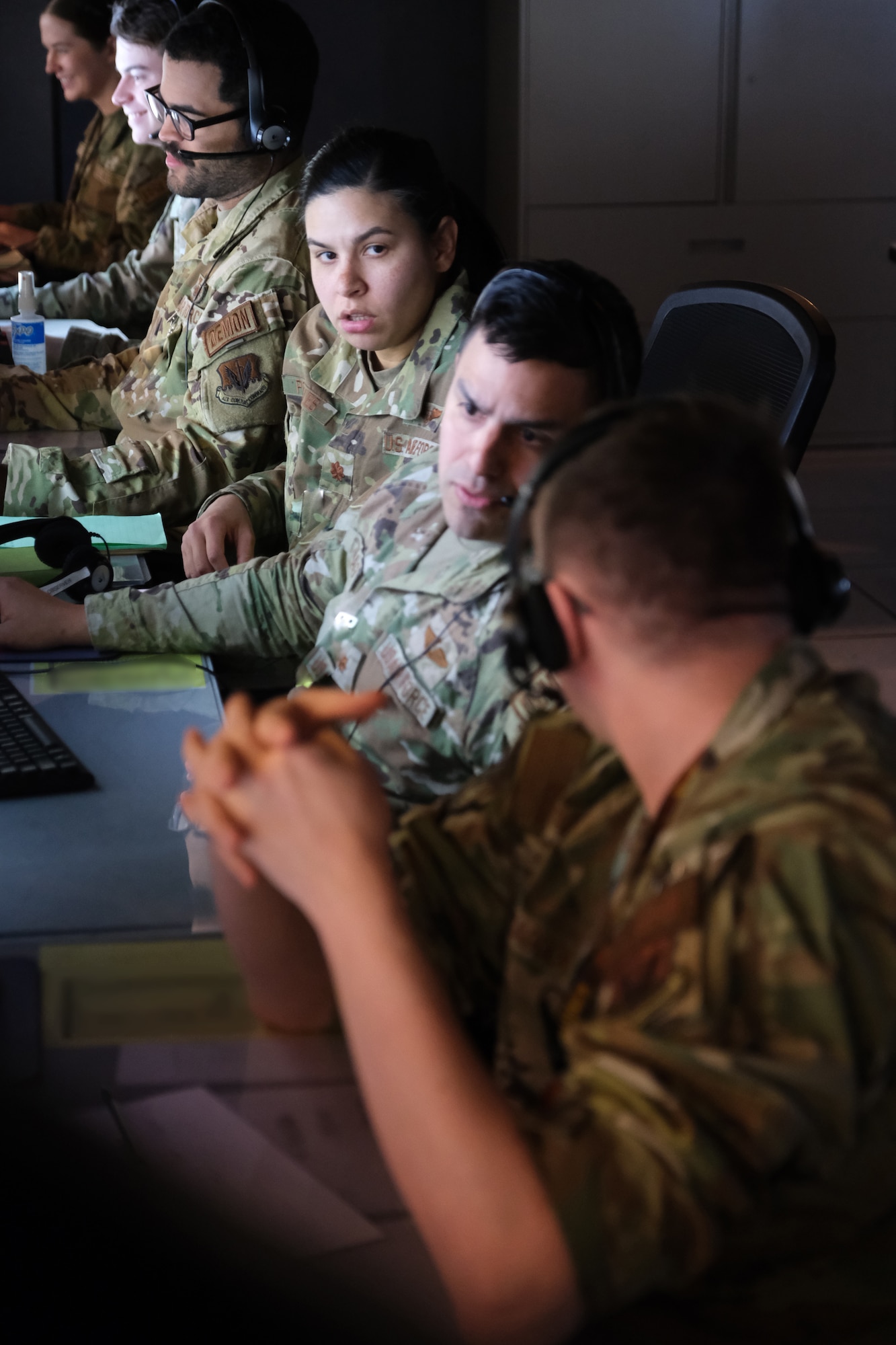 photo of US military personnel wearing headphones working at computers