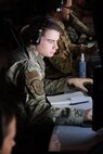 photo of US military personnel wearing headphones working at computers