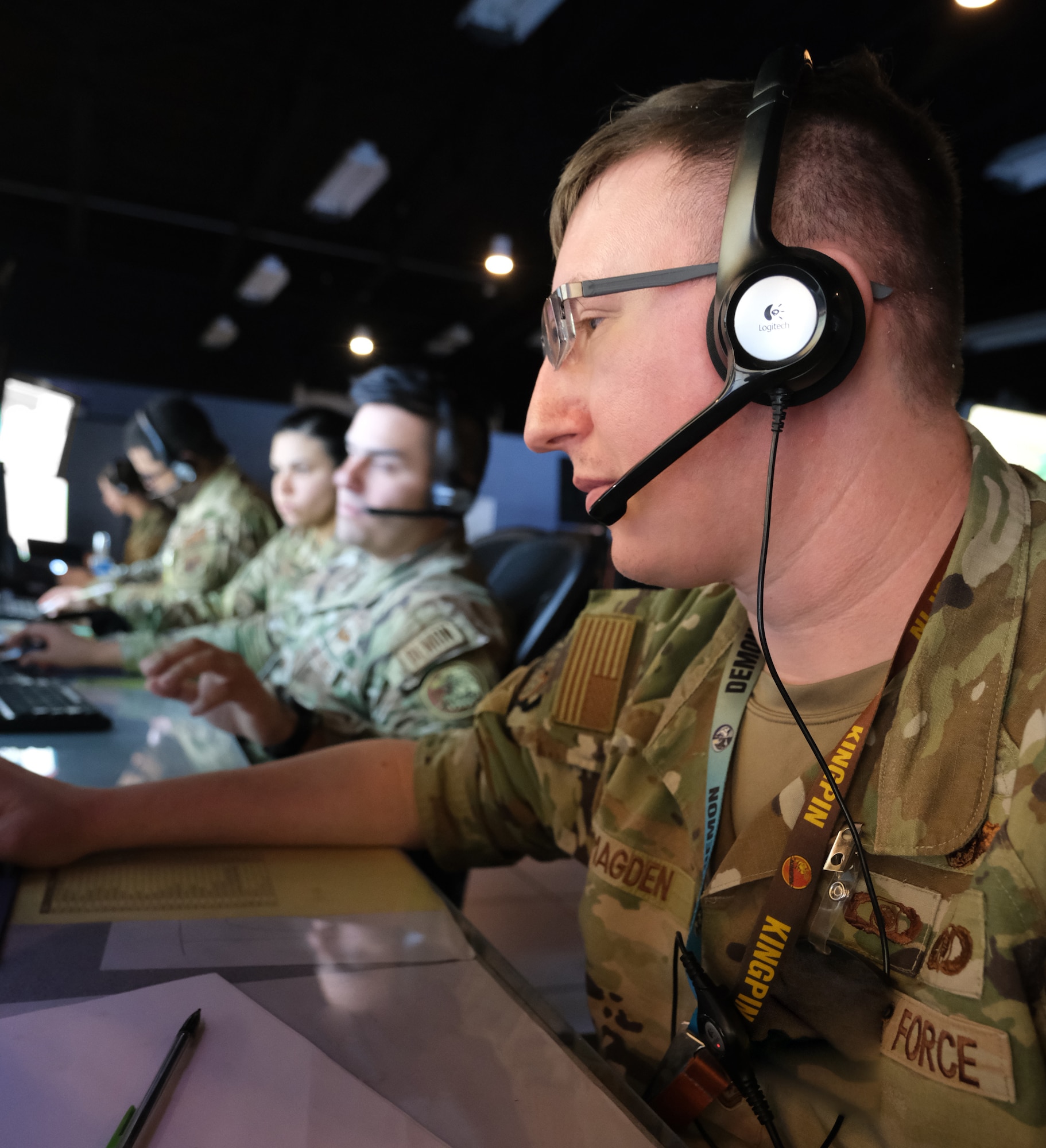 photo of US military personnel wearing headphones working at computers
