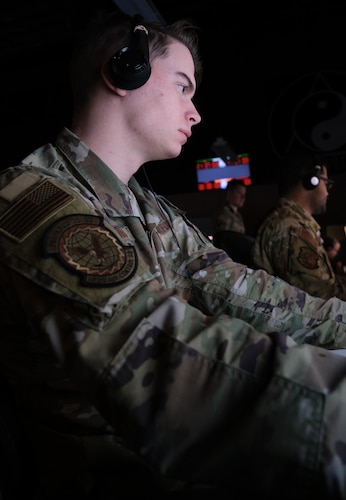 photo of US military personnel wearing headphones working at computers
