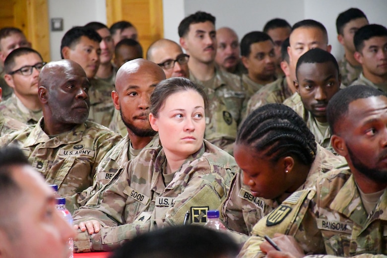 Female U.S. Army Soldier looking over shoulder listening while seated at a table.