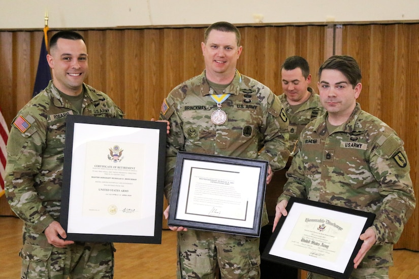 Master Sgt. Nicholas Brinckman (center) is presented with certificates of honorable discharge, retirement, and appreciation by Master Sgt. Carlos Rosario (left) and Sgt. 1st Class Mark Rumler (right) during his retirement ceremony at Fort Indiantown Gap, Pa. April 8, 2024. (U.S. Army National Guard photo by Sgt. 1st Class Shane Smith)