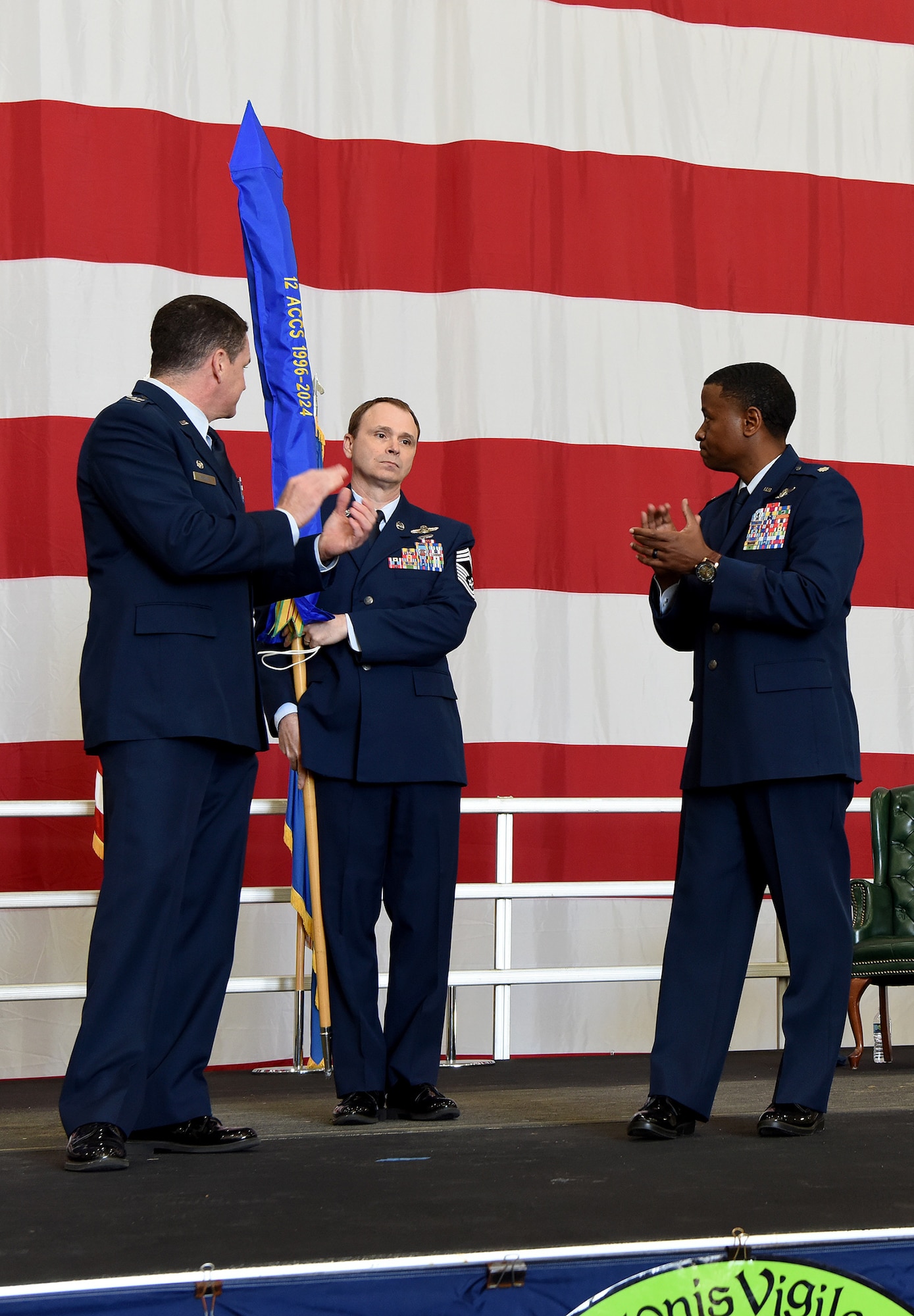 Three people in military uniform standing on stage