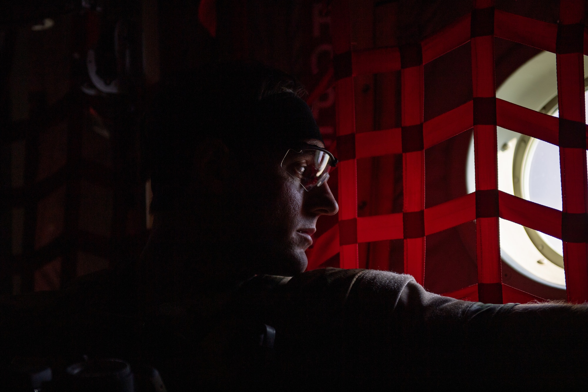 A U.S. Air Force Airman assigned to the 38th Rescue Squadron looks out a window of an HC-130J Combat King II during Exercise Ready Tiger 24-1 at Savannah Air National Guard Base, Georgia, April 11, 2024. The exercise simulated a downed pilot scenario which tested the combat search and rescue team’s ability to respond at a moment's notice from a forward operating site. During Ready Tiger 24-1, exercise inspectors will assess the 23rd Wing's proficiency in employing decentralized command and control to fulfill air tasking orders across geographically dispersed areas amid communication challenges, integrating Agile Combat Employment principles such as integrated combat turns, forward aerial refueling points, multi-capable Airmen, and combat search and rescue capabilities. (U.S. Air Force photo by Senior Airman Courtney Sebastianelli)