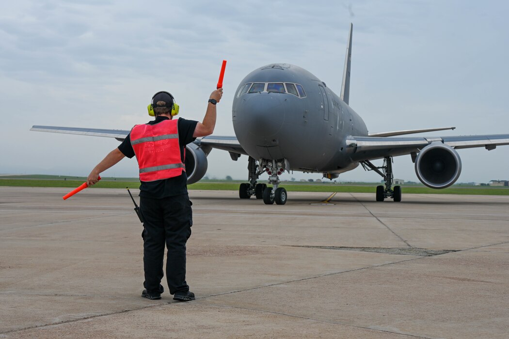 Braden Malloy, 97th Maintenance Squadron aircraft attendant, marshals a KC-46 Pegasus on the flightline at Altus Air Force Base, Oklahoma, April 15, 2024. The 97th Maintenance Group generated 27 aircraft for the real-world weather evacuation. (U.S. Air Force photo by Senior Airman Trenton Jancze)