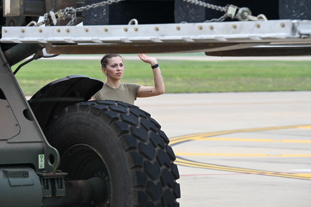 U.S. Air Force Airman Bethanie Boggs, 97th Logistic Readiness Squadron Aerial Operations Flight aerial operations apprentice, motions a forklift towards a Tunner 60K Aircraft Loader on the flightline at Altus Air Force Base, Oklahoma, April 15, 2024. The Aerial Operations Flight is the largest air transportation footprint outside of Air Mobility Command, comprised of 78 Airmen that perform Air Freight, Aerial Delivery, Fleet and Passenger Service operations. (U.S. Air Force photo by Senior Airman Trenton Jancze)